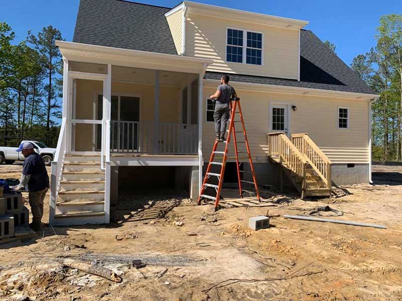Precision Trim of Virginia Inc. workers about to work on a home: one of them is on a ladder inspecting the side of the home